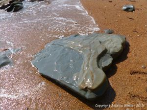 Beach boulder in shingle at the water's edge