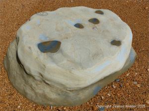 Beach boulder on wet shingle at the beach