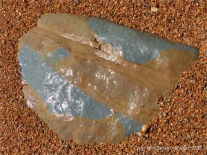 Beach boulder in shingle at the water's edge
