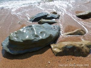 Beach boulders in shingle at the water's edge