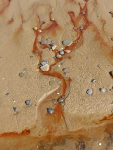 Red liquid draining from the beach at Whiteford Sands