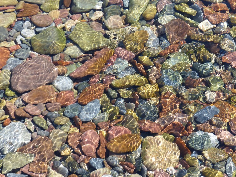 Coloured pebbles under water on a sunny day