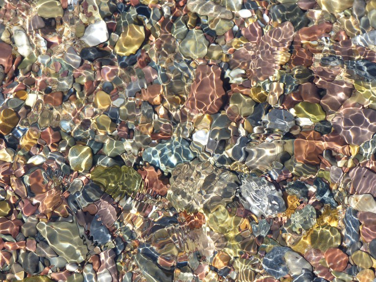 Coloured pebbles under water on a sunny day
