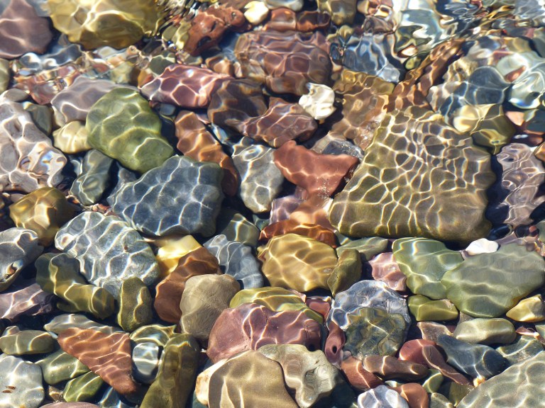 Coloured pebbles under water on a sunny day