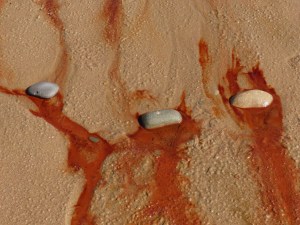 Red liquid draining from the beach at Whiteford Sands