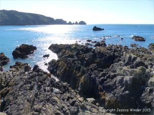 View across the rocky beach outcrops at Moulin Huet Bay towards the Pea Stacks