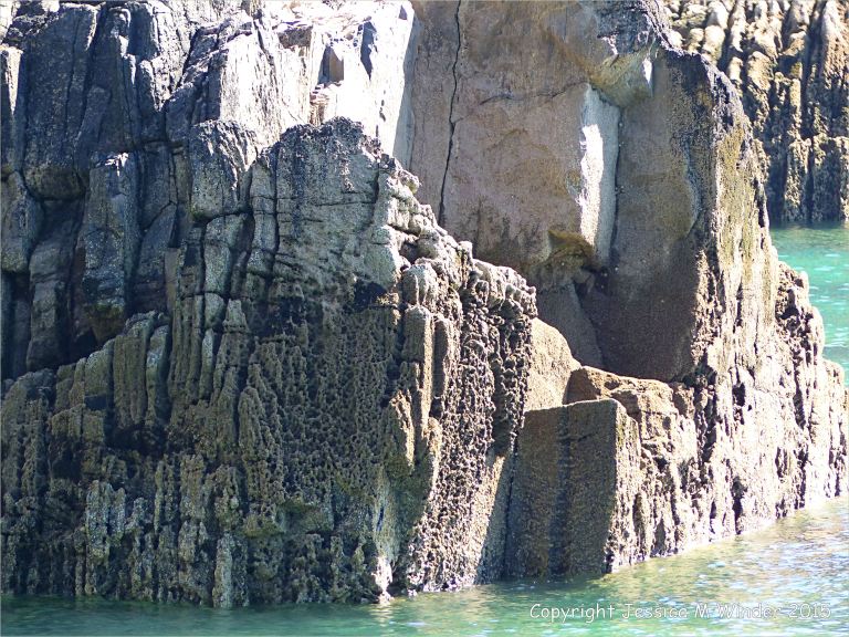Carboniferous Black Rock Limestone with bioerosion on the waterline around the natural Horseback arch on the seashore at Church Doors on the South Pembrokeshire Coast in Wales
