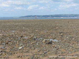 View looking towards the lighthouse at Whiteford on the Gower Peninsula showing rock strewn beach