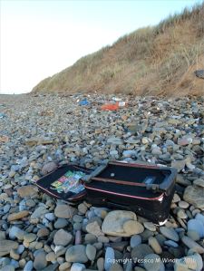 Flotsam suitcase on beach pebbles