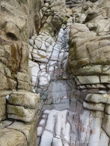 Gully of water-worn limestone rock layers on the Worms Head Causeway in Gower, South Wales.