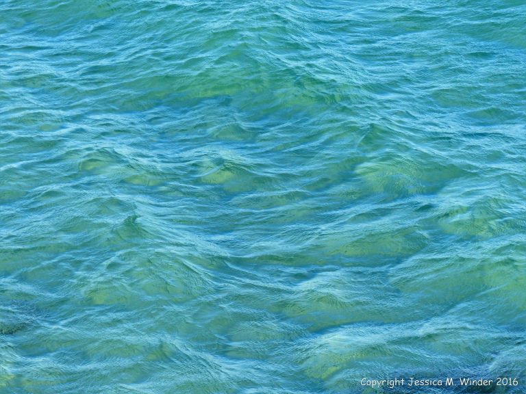 Texture and pattern of blue sea water over a yellow sandy shore