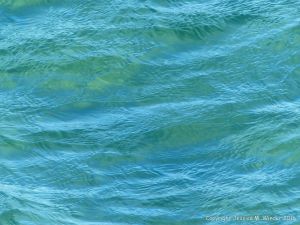Texture and pattern of blue sea water over a yellow sandy shore