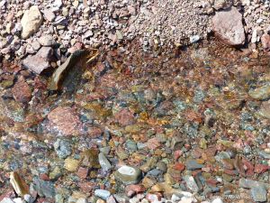 Stream across the red pebbles on the beach at Wasson Bluff