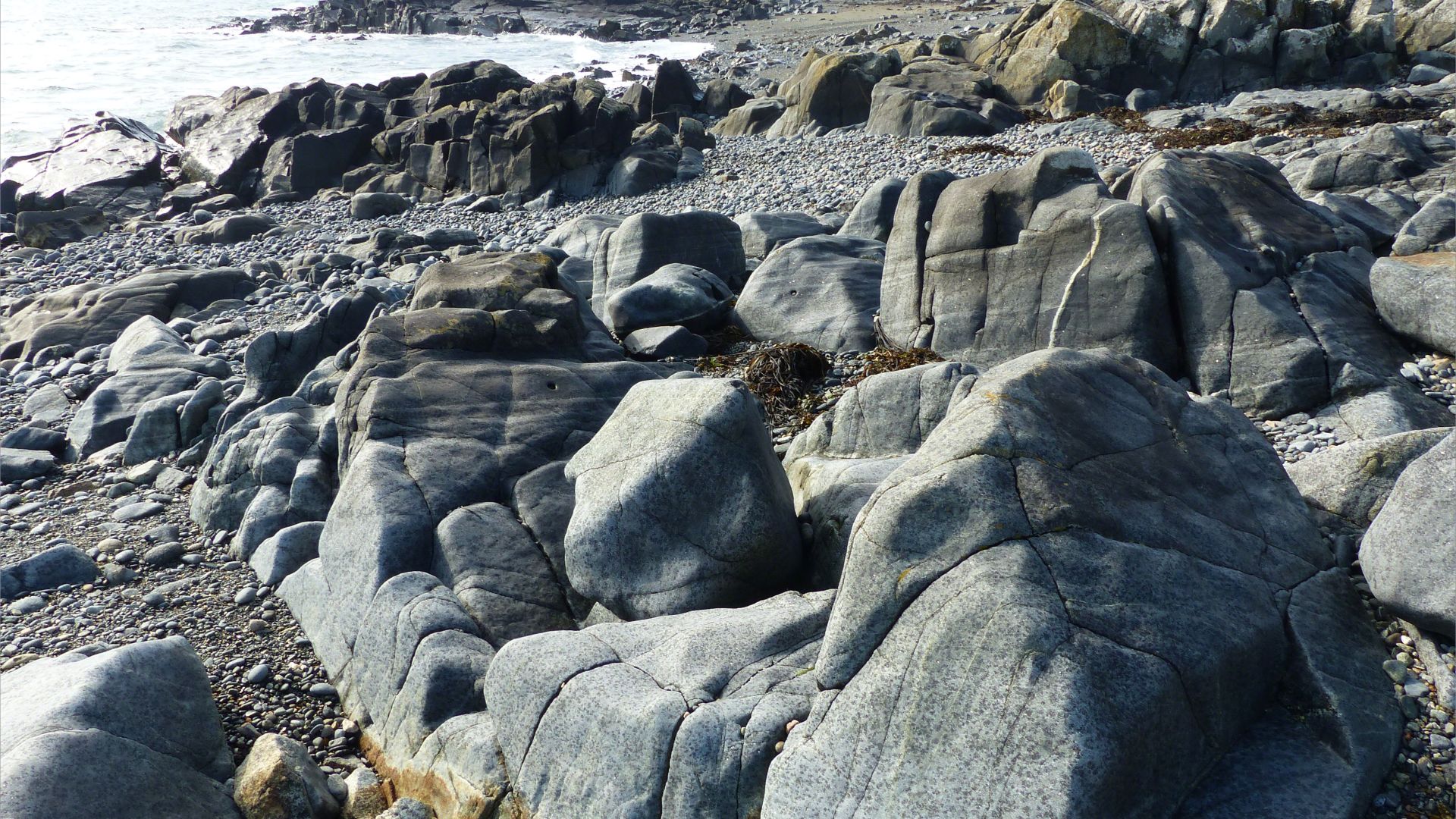 Outcrops of St Peter Port Gabbro on the shore at Spur Bay in the Channel Island of Guernsey, showing crystals aligned into bands.