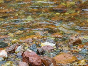 Water flowing over colourful riverbed stones at the Lone Shieling