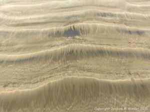 Natural patterns left by the ebbing tide on a sandy beach