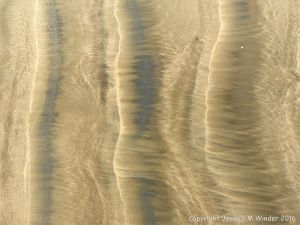 Natural patterns left by the ebbing tide on a sandy beach