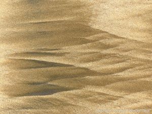 Natural patterns left by the ebbing tide on a sandy beach