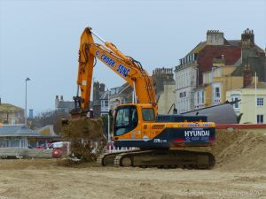 Mechanical digger moving fresh sand on Weymouth Beach
