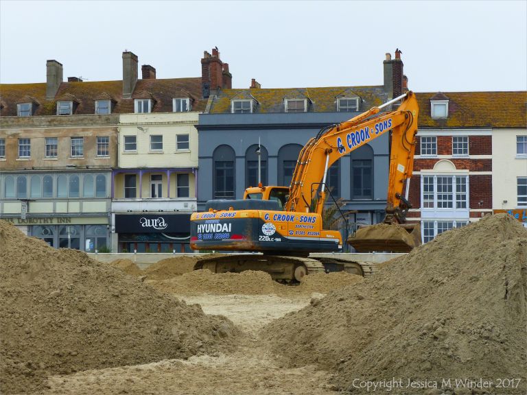 Mechanical digger moving fresh sand on Weymouth Beach