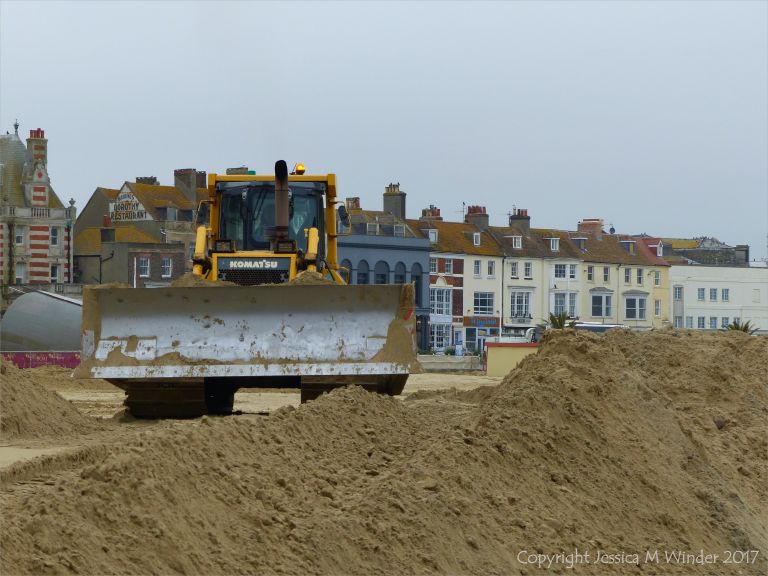 Mechanical digger moving fresh sand on Weymouth Beach