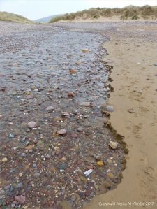 Beach stream with pebbles running through sand