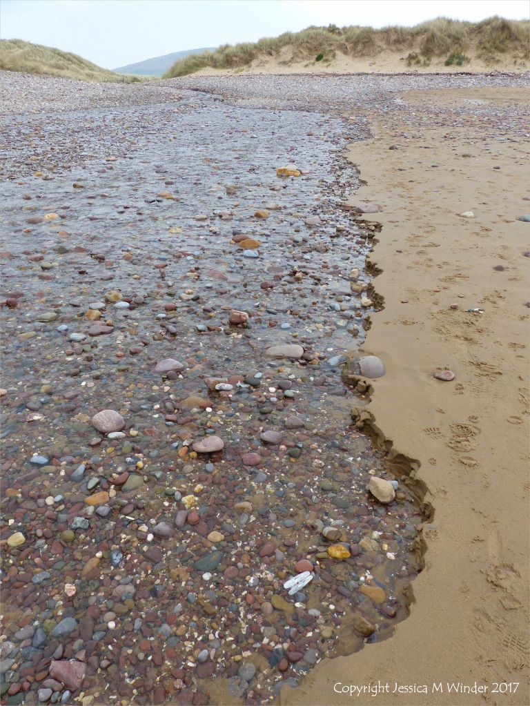 Beach stream with pebbles running through sand