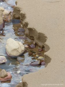 Scalloped sandy edge to a beach stream