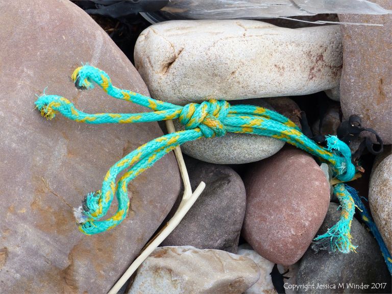 Piece of green knotted rope on pebbles at Rhossili