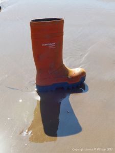 Orange wellington boot flotsam on a sandy beach