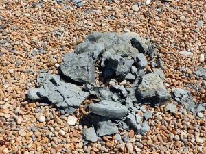 Lump of dry shattered Eype Clay on a pebble beach