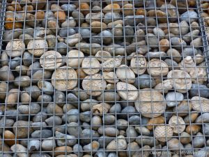 Natural pebbles and decorative hand-made ceramic pebbles in wire cages called gabions