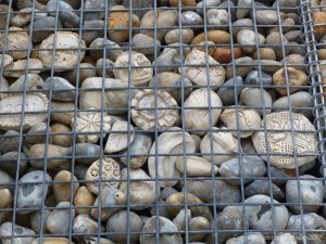 Natural pebbles and decorative hand-made ceramic pebbles in wire cages called gabions