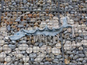 Natural pebbles and decorative hand-made ceramic pebbles in wire cages called gabions