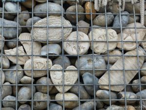 Natural pebbles and decorative hand-made ceramic pebbles in wire cages called gabions