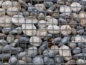 Natural pebbles and decorative hand-made ceramic pebbles in wire cages called gabions