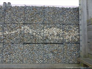 Natural pebbles and decorative hand-made ceramic pebbles in wire cages called gabions