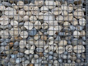 Natural pebbles and decorative hand-made ceramic pebbles in wire cages called gabions