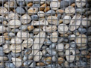 Natural pebbles and decorative hand-made ceramic pebbles in wire cages called gabions