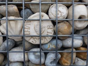 Natural pebbles and decorative hand-made ceramic pebbles in wire cages called gabions