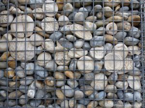 Natural pebbles and decorative hand-made ceramic pebbles in wire cages called gabions