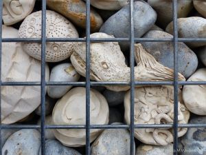 Natural pebbles and decorative hand-made ceramic pebbles in wire cages called gabions