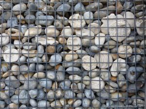 Natural pebbles and decorative hand-made ceramic pebbles in wire cages called gabions