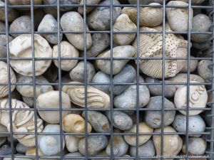 Natural pebbles and decorative hand-made ceramic pebbles in wire cages called gabions