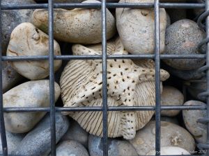 Natural pebbles and decorative hand-made ceramic pebbles in wire cages called gabions