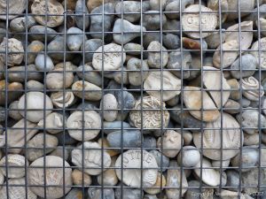 Natural pebbles and decorative hand-made ceramic pebbles in wire cages called gabions