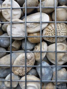 Natural pebbles and decorative hand-made ceramic pebbles in wire cages called gabions