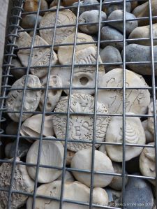 Natural pebbles and decorative hand-made ceramic pebbles in wire cages called gabions