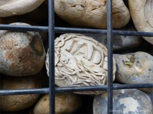 Natural pebbles and decorative hand-made ceramic pebbles in wire cages called gabions