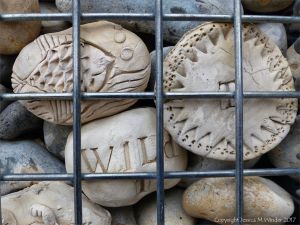 Natural pebbles and decorative hand-made ceramic pebbles in wire cages called gabions